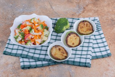 Tabakta kızarmış kabak dilimleri, brokoli dilimleri ve mermer zemin üzerinde bir kase sebze salatası. Yüksek kalite fotoğraf