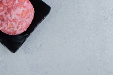 Mermer arka planda siyah tabakta lezzetli pembe bir kurabiye. Yüksek kalite fotoğraf