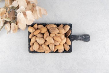 Yaprakların yanında mermer zemin üzerinde bir tepsi badem. Yüksek kalite fotoğraf