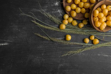 Ahşap tabakta sarı erik yığını, üst manzara.