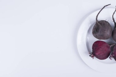 Sağ tarafta beyaz bir tabakta tam ve yarım pancar kökü. Yüksek kalite fotoğraf