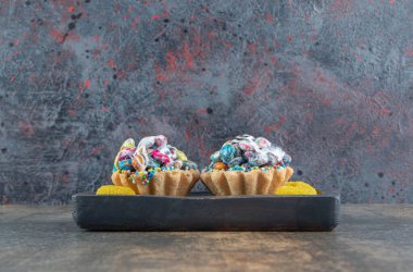 Koyu ahşap bir tahtanın üzerinde kalp şeklinde şekerler olan lezzetli kekler. Yüksek kalite fotoğraf