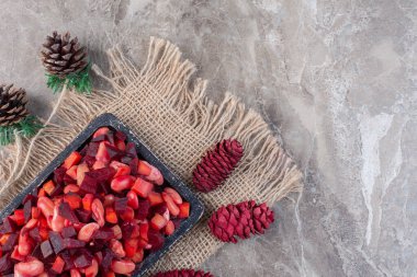 Mermer arka planda eskimiş sirke salatası tepsisinin etrafında renkli çam kozalakları. Yüksek kalite fotoğraf