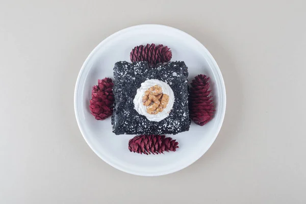 Chocolate cake and red pine cones on a platter on marble background. High quality photo