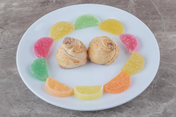 Marmelades around tiny cakes on a platter on marble background. High quality photo