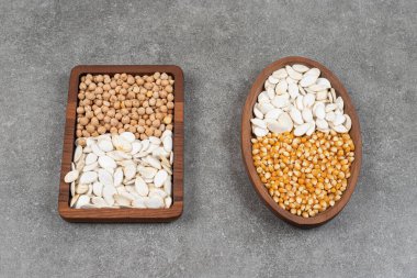 İki tabak çiğ mısır, bezelye ve mermer zemin üzerinde kabak çekirdeği. Yüksek kalite fotoğraf