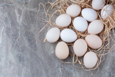 Mermer arka planda samanlı birkaç tane taze tavuk yumurtası. Yüksek kalite fotoğraf