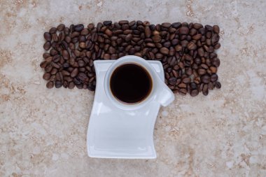 Bir fincan sade kahve ve mermer arka planda bir yığın kahve çekirdeği. Yüksek kalite fotoğraf