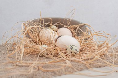 Bıldırcın yumurtalı tavuk taze beyaz yumurta ve gri tabakta saman. Yüksek kalite fotoğraf