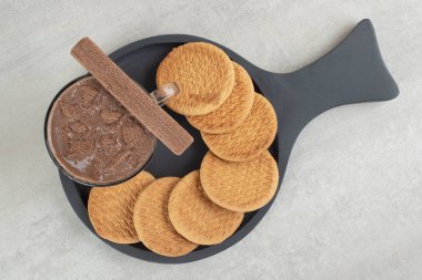 Koyu tahtada bir bardak kahve ve çeşitli bisküviler. Yüksek kalite fotoğraf