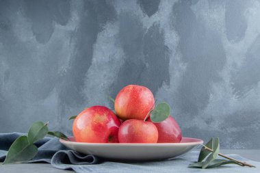 Mermer zemin üzerinde bir parça kumaş üzerinde bir tepside küçük bir elma yığını. Yüksek kalite fotoğraf