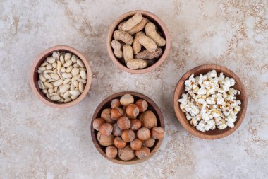 Fındık, fıstık, ayçekirdeği ve mermer yüzeyde patlamış mısır kaseleri. Yüksek kalite fotoğraf