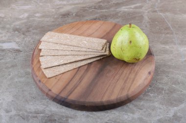 Tahtada cips ve armut var, mermer arka planda. Yüksek kalite fotoğraf