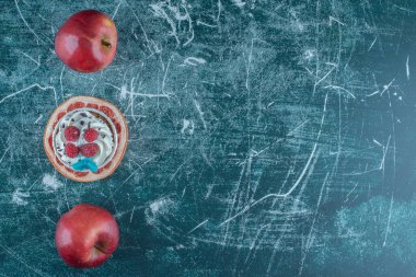 Mavi arka planda bir dilim greyfurt üzerine iki elma ve bir kek. Yüksek kalite fotoğraf