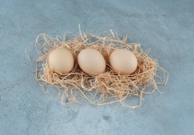 Mermer zemin üzerinde saman yığını üzerinde bir avuç dolusu yumurta. Yüksek kalite fotoğraf