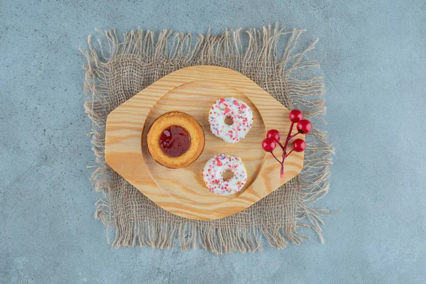 大理石の背景に木製の皿の上にスナックサイズのドーナツとゼリーでいっぱいのケーキ 高品質の写真 — ストック写真