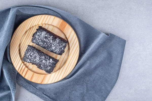Chocolate cake slices on a wooden platter on a towel on marble background. High quality photo