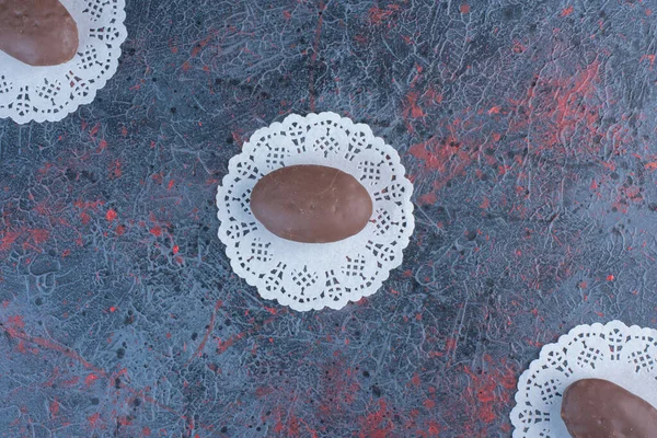 Chocolate coated cakes on doilies on abstract background. High quality photo