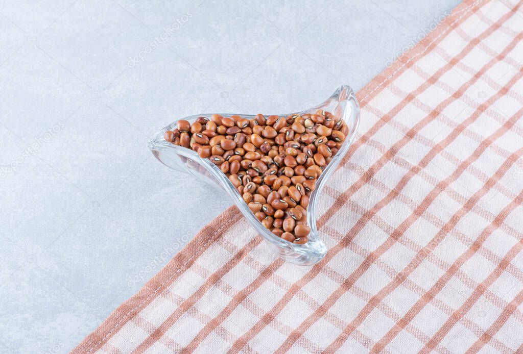Small trinagular snack plate full of red beans on tablecloth, on marble background. High quality photo