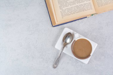 Bir fincan sütlü kahve, bir kaşık ve taş zemin üzerine kitap. Yüksek kalite fotoğraf