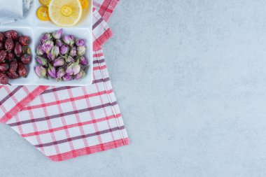 Çay poşetleri, dilimlenmiş limon, kuru gül suyu ve mermer arka planda, kasenin üzerinde çiçek. Yüksek kalite fotoğraf