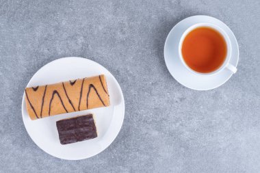 Beyaz tabakta çikolata ve bir fincan çayla nefis bir rulo pasta. Yüksek kalite fotoğraf