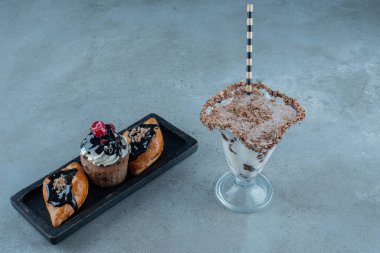 Karanlık tahtada keklerin olduğu nefis tatlı bir içecek. Yüksek kalite fotoğraf