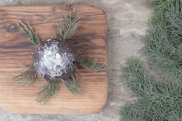 Chocolate coated cake, wooden board and pine branches on marble background. High quality photo