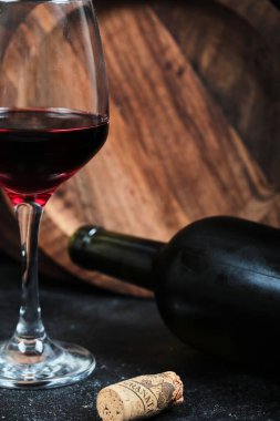 Koyu arkaplanda bir kadeh şarap ve ahşap tabakla. Yüksek kalite fotoğraf