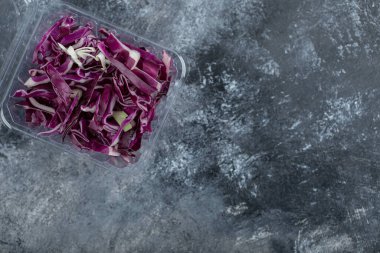 Gri arka planda taze doğranmış mor lahanayla dolu plastik kabın en üst görüntüsü. Yüksek kalite fotoğraf