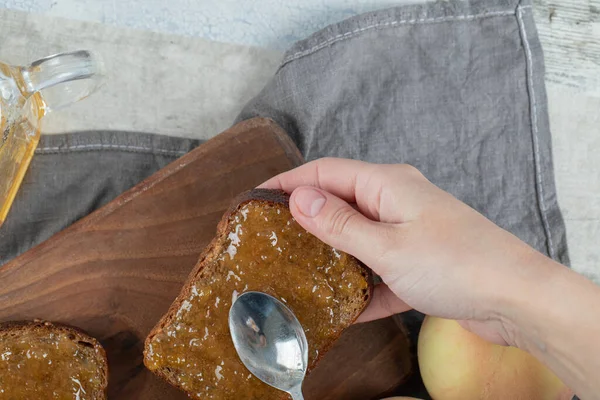 在木制切菜板上夹着桃子果酱的褐色面包片 高质量的照片 — 图库照片