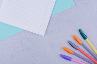 Gri arka planda renkli kalemler olan boş bir defter. Yüksek kalite fotoğraf