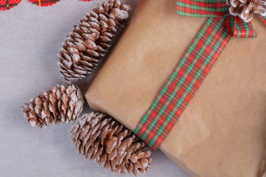 Beyaz yüzeyde çam kozalağıyla süslenmiş Noel hediyesi kutuları. Yüksek kalite fotoğraf