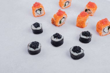 Maki ve California suşisi beyaz arka planda yuvarlanıyor. Yüksek kalite fotoğraf