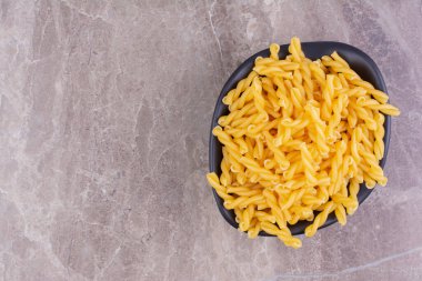 Gri arka planda izole edilmiş siyah bir seramik kasede makarna. Yüksek kalite fotoğraf