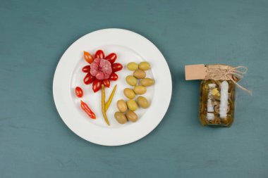 Bir kavanoz jalapeno turşusu ve marine edilmiş domates, sarımsak, mavi arka planda zeytin tabağı. Yüksek kalite fotoğraf