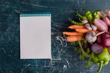 Mavi arka planda izole edilmiş çeşitli sebzeler ve yemek tarifi kitapları. Yüksek kalite fotoğraf