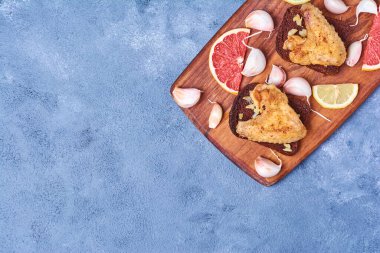 Mavi arka planda ahşap bir tahtada kızarmış tavuk kanadı. Yüksek kalite fotoğraf