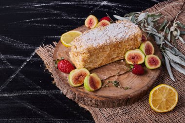 İncir ve yün masa örtüsünün üzerinde yapraklar olan bir dilim Napoelon pastası. Yüksek kalite fotoğraf