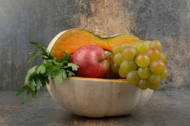 Arkaplanda elma ve üzüm dolu bir balkabağı