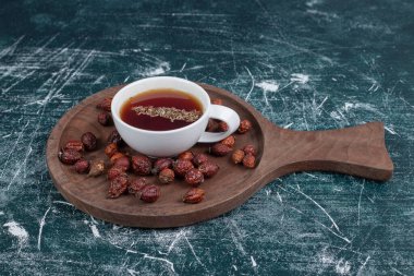 Kurumuş gül kalçası ve tahta tahtada bir fincan çay. Yüksek kalite fotoğraf