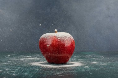Mavi arka planda pudra ile süslenmiş kırmızı elma. Yüksek kalite fotoğraf