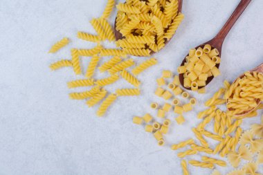  Beyaz arka planda çeşitli makarna şekilleri ve kaşıklar. Yüksek kalite fotoğraf