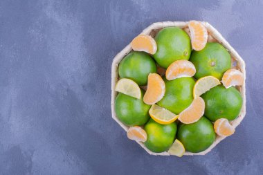 Mavi arka planda, bambu tabakta yeşil mandalinalar. Yüksek kalite fotoğraf