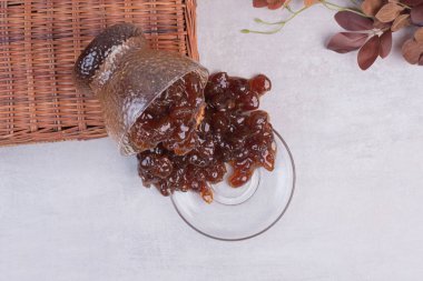 Beyaz yüzeyinde yaprakları olan bir bardak meyve reçeli ve çay tabağı. Yüksek kalite fotoğraf