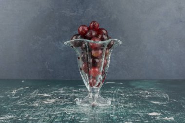 Mermer masanın üzerinde camda siyah üzümler var. Yüksek kalite fotoğraf