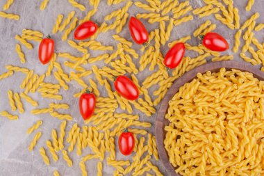 Mermer zemin üzerinde kiraz domatesli çiğ makarnalar. Yüksek kalite fotoğraf