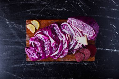 Ahşap bir tahtanın üzerinde siyah bir arka planda dilimlenmiş mor lahana. Yüksek kalite fotoğraf