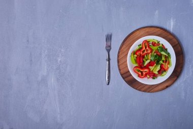 Ahşap bir tahtanın üzerinde mavi arka planda kesilmiş sebze salatası. Yüksek kalite fotoğraf