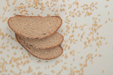 Beyaz zemin üzerinde yulaf taneleri olan dilimlenmiş taze kahverengi ekmek. Yüksek kalite fotoğraf